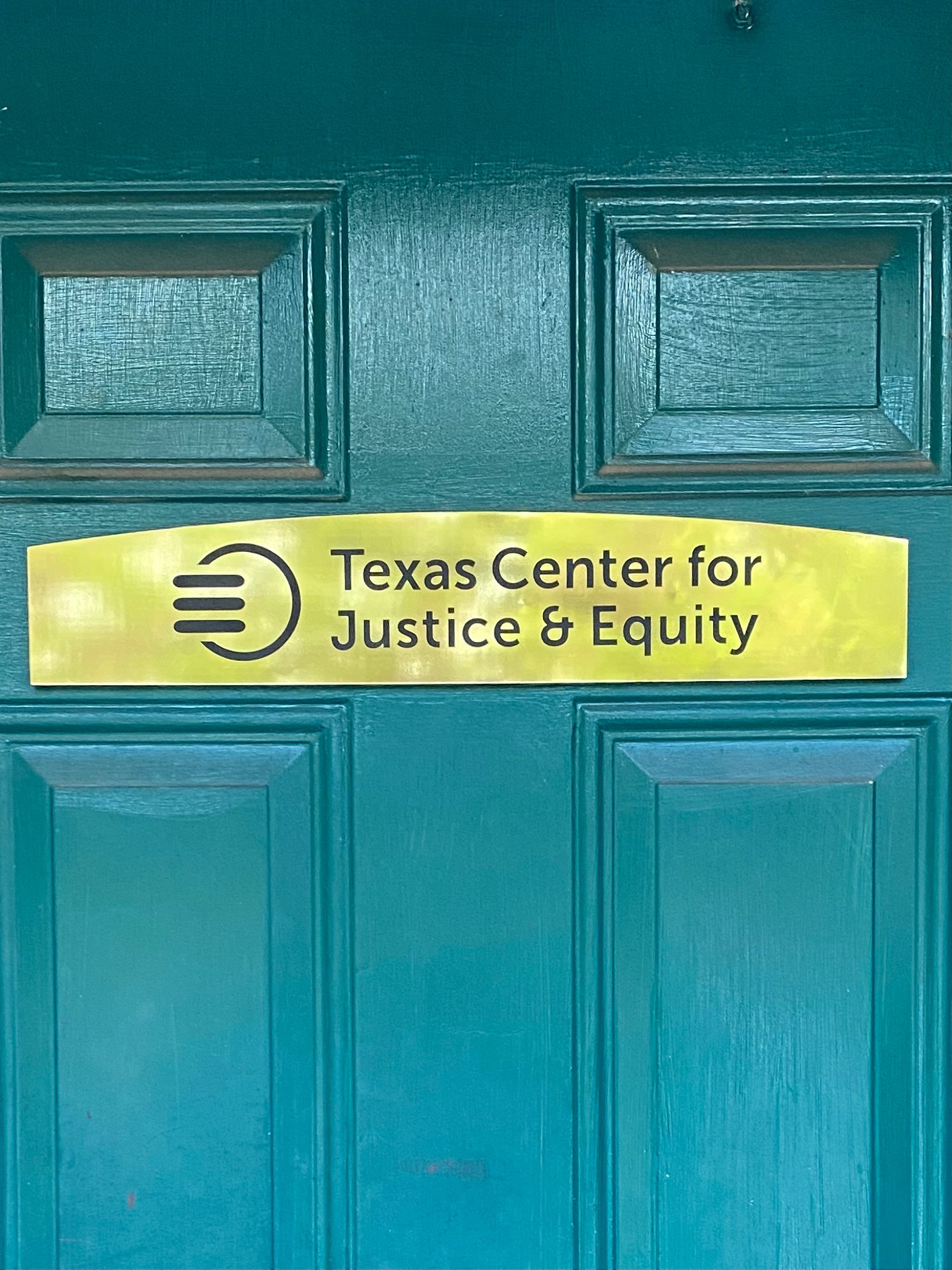 Green door with sign reading Texas Center for Justice and Equity