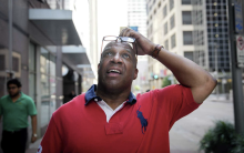 Demetrius stands outside in the city looking up at the sky [photo by Houston Chronicle]
