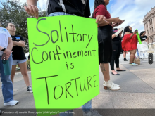 Poster protesting solitary confinement being held by protestor